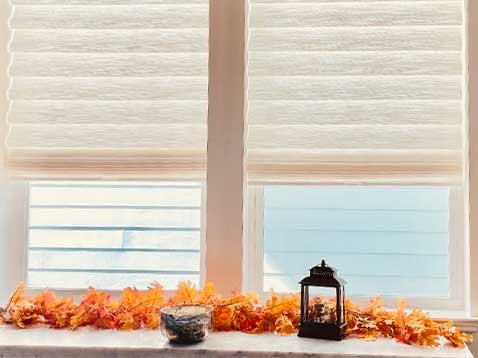 A window sill covered in autumn leaves and a lantern