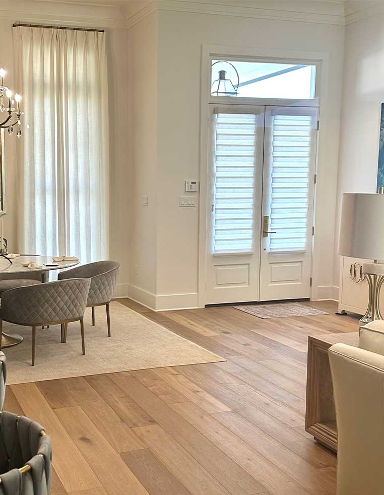 Bright living room space, showcasing window drapes and shutters